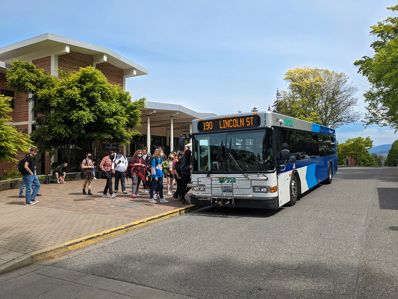 Students board the WTA 190 bus to Lincoln Street in front of the Viking Union. The sky is blue and the sun is out.