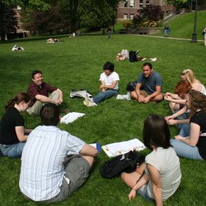 A class gathers outside for a discussion in front of Old Main